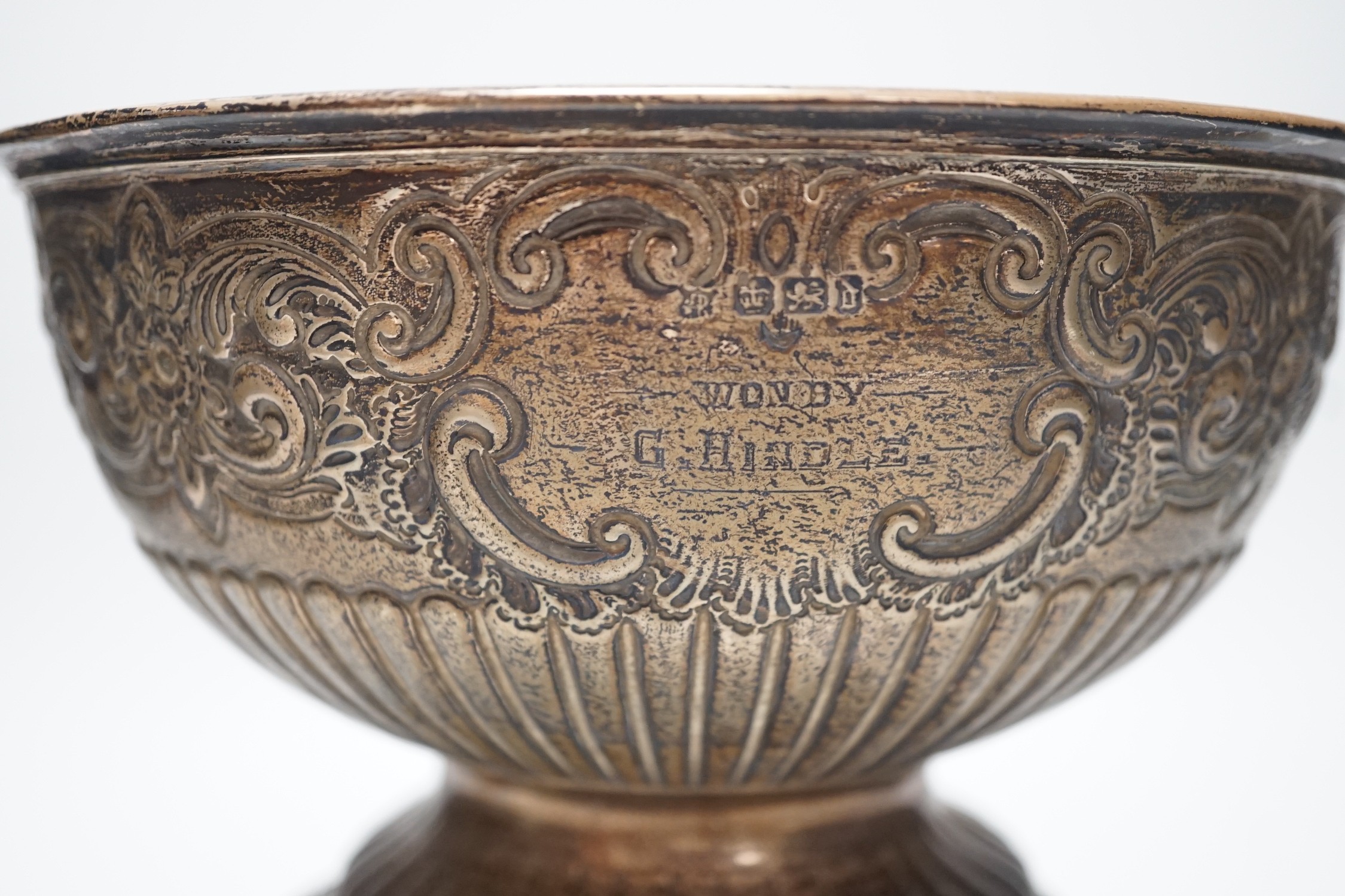 A late Victorian demi fluted and embossed silver presentation rose bowl, with engraved inscription, James Deakin & Sons, Sheffield, 1896, diameter 19.5cm, 12.2oz, on ebonised plinth